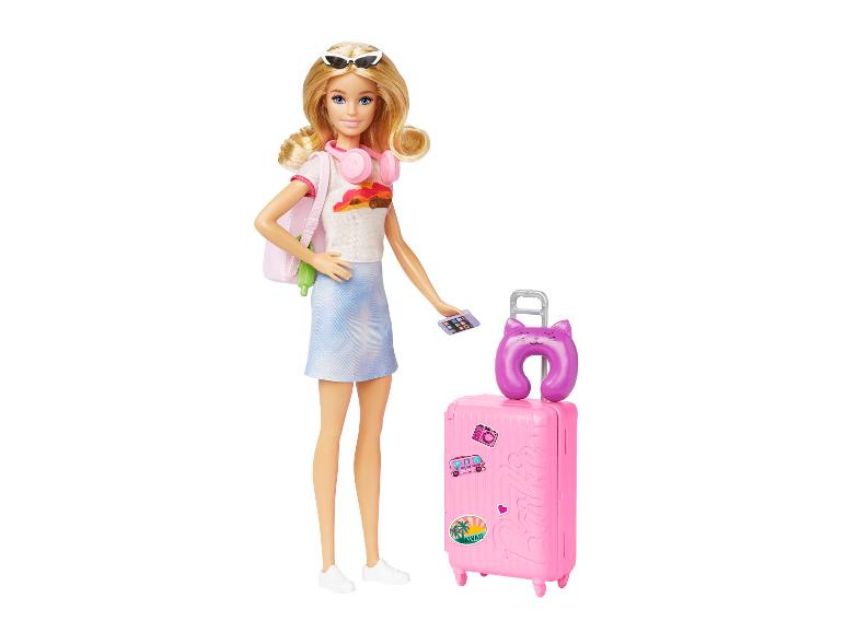 Pop met blond haar, zonnebril, roze koptelefoon, wit t-shirt, blauwe rok en roze koffer.