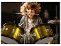 Een enthousiast kind speelt op gouden drums met een brede glimlach.