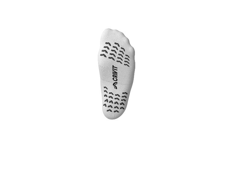 Witte antislipsok met zwarte zool met patroon.