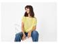 Vrouw in geel T-shirt en blauwe jeans, zittend op een witte stoel.