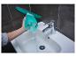Hand giet water in turquoise raamwisser boven witte wastafel met kraan.
