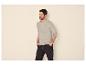Man in een lichtgrijs Henley-shirt met lange mouwen en donkere jeans, handen in zakken.