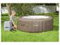 Vrouw blaast een bruine opblaasbare jacuzzi op groen gras op.