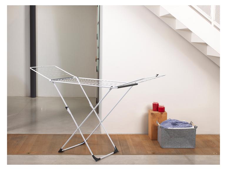 Wit wasrek met grijze wasmand en rode kaarsen.