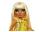 Pop met blond haar en grote ogen, in een gele en gouden jurk.