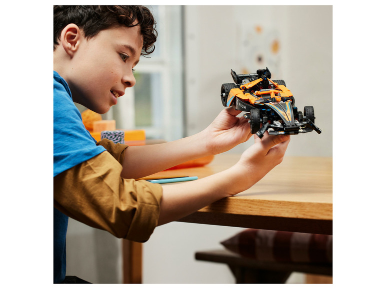Een jongen houdt een LEGO Technic McLaren Formule 1 auto vast.