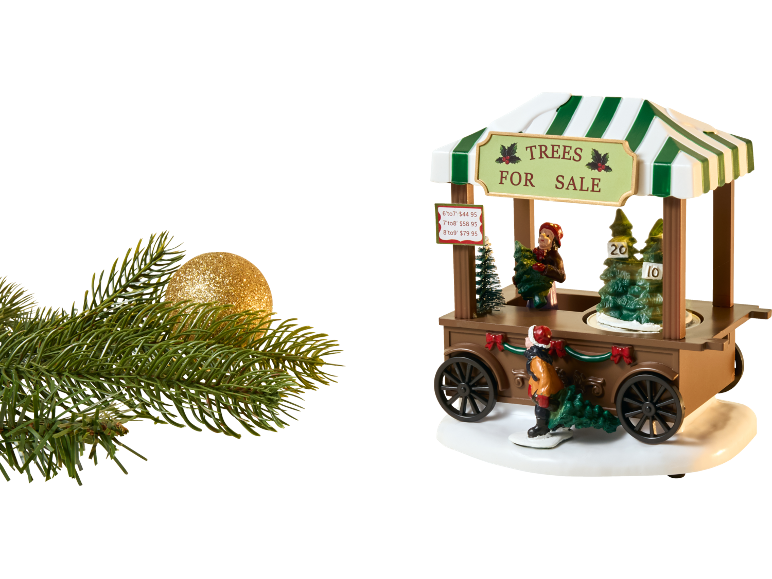 Kerstboomverkoopkraam met miniatuurfiguren, bomen en een prijslijst, naast een glittergouden ornament en dennentak.
