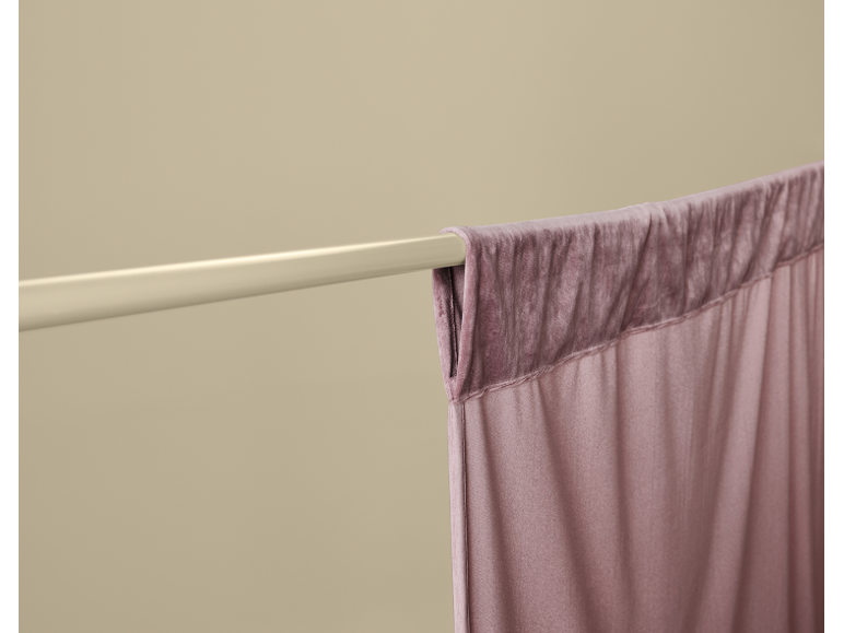 Roze gordijn hangend aan een crèmekleurige roede, met zachte, geplooide stof.