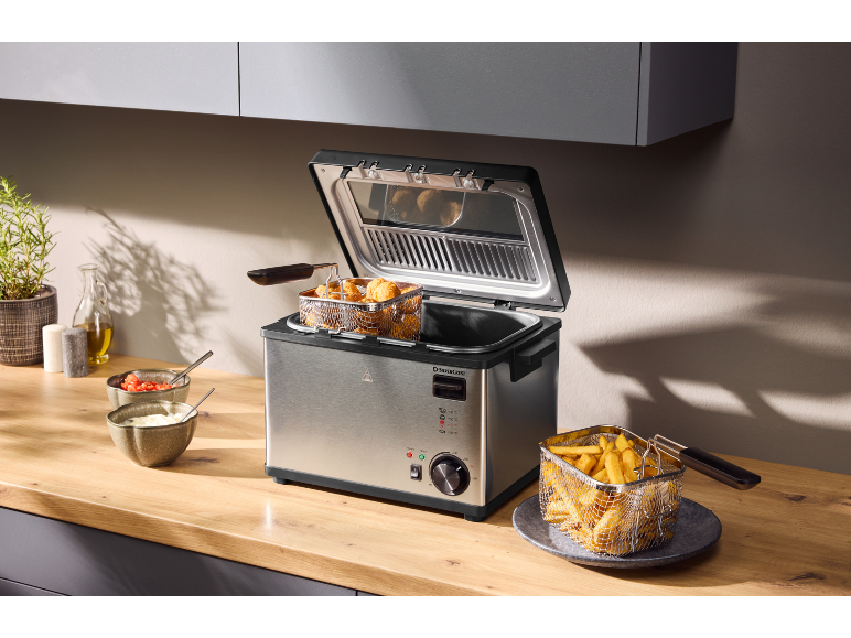Roestvrijstalen friteuse met kipnuggets en frietjes in een keuken.