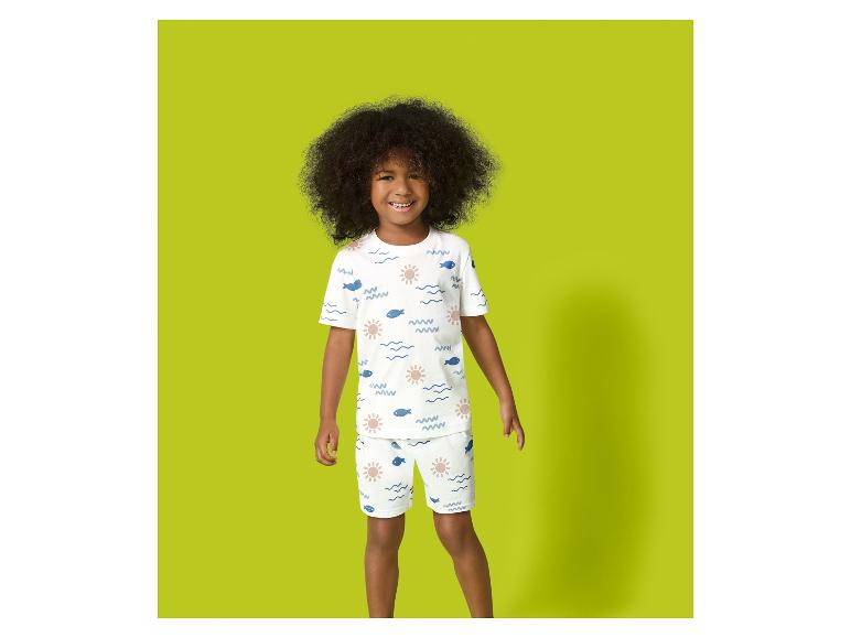 Kind in witte pyjama met zon- en vissenprint.