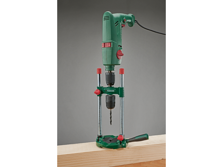 Groene boormachine in een boorstandaard, klaar om in een houten plank te boren.