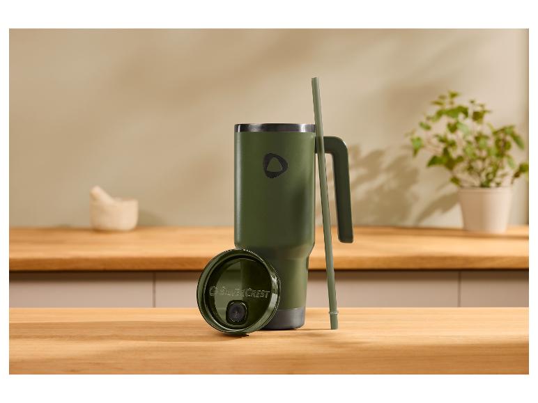 Groene thermosbeker met handvat en rietje op houten aanrecht, deksel met tekst