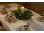 Elegant gedekte kersttafel met een kaars, een feestelijke krans en stijlvol servies.