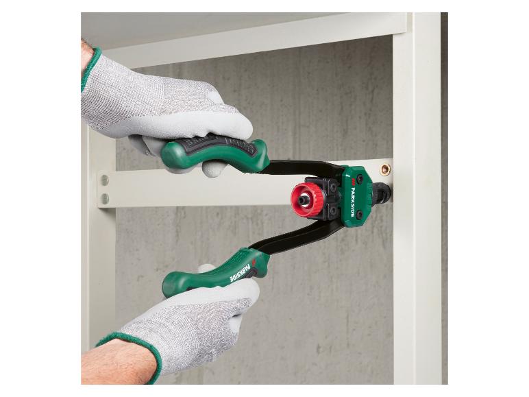 Grijze werkhandschoenen gebruiken een groene handniettang om een metalen onderdeel aan een plank te bevestigen.