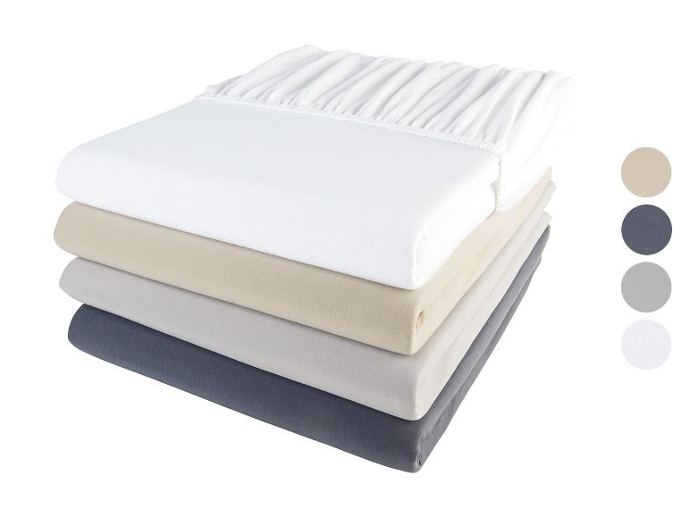 Een stapel witte, beige, grijze en donkergrijze hoeslakens