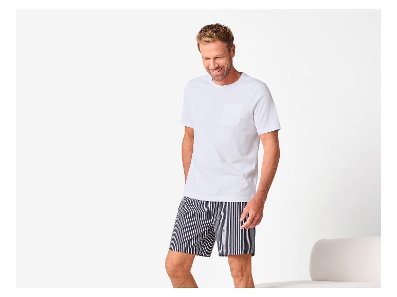Man in wit T-shirt en gestreepte korte broek, lachend.