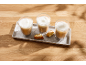 Drie glazen koffie met melk en koekjes op een betonnen dienblad.