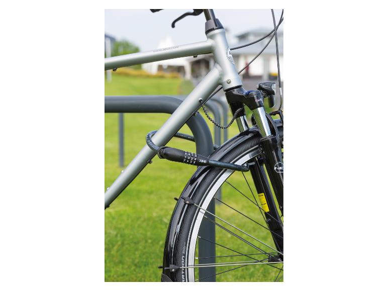 Stadsfiets met cijferslot, vastgemaakt aan een fietsenrek op een gazon.