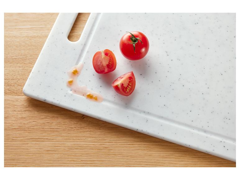 Verse, hele en gesneden tomaten op een witte snijplank, met tomatensap