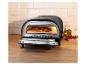 Pizzaoven met een pizza erin, olijfolie en tomaten op een houten plank.
