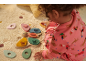 Baby speelt met houten vlindervormige sorteerspeelgoed op een licht tapijt.