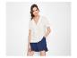 Vrouw in een wit overhemd met korte mouwen en blauwe shorts.