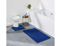 Badkamer met blauwe badmatten en een wit toilet.