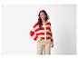 Vrouw in rood-wit gestreept gebreid vest en beige broek