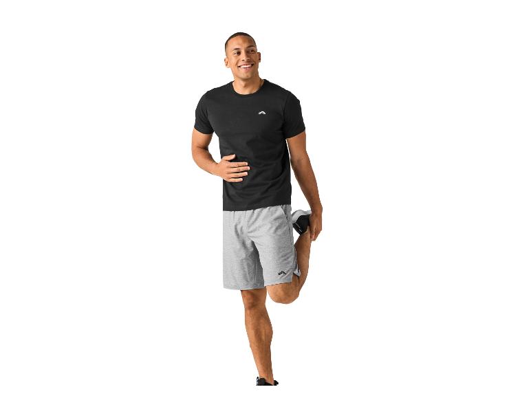 Man in zwart T-shirt en grijze shorts rekt zijn been.