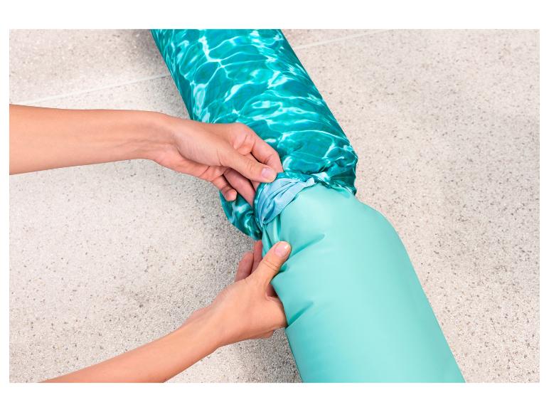 Een turquoise opblaasbaar zwembadmatras met waterpatroon klaarmaken.