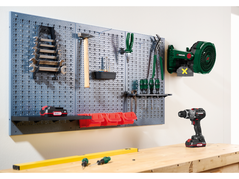 Geperforeerd paneel met werkplaatsgereedschap, inclusief moersleutels, hamer, schroevendraaiers en accuboormachine.