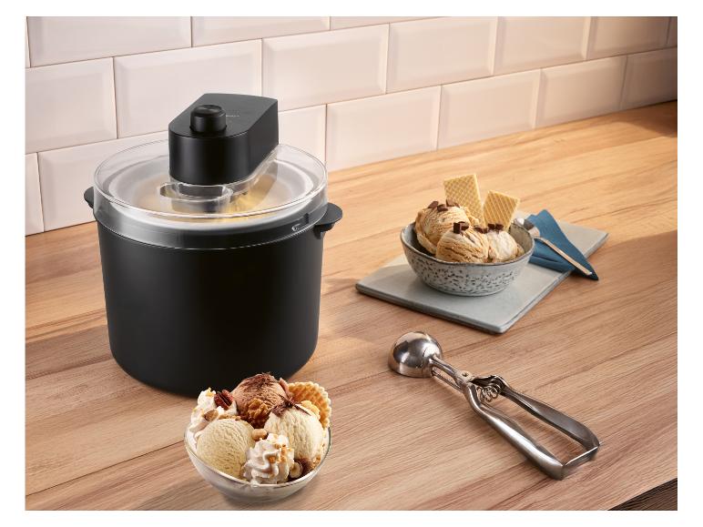 IJs machine met twee kommen ijs, wafels en ijsschep op houten aanrecht.