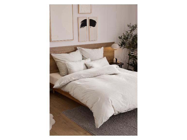 Slaapkamer met bed met licht beddengoed, nachtkastje en kunst aan de muur.