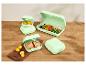 Groene voedselcontainers met sandwiches, olijven, garnalen en kumquats op een houten tafel.