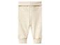 Lichtbeige geribbelde babybroek met brede, omvouwbare tailleband en boorden bij de enkels.