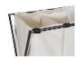 Close-up van een beige wasmand met drie compartimenten en een zwart metalen frame.