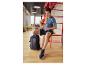 Man in sportkleding zittend, met rugzak en sneakers ernaast.