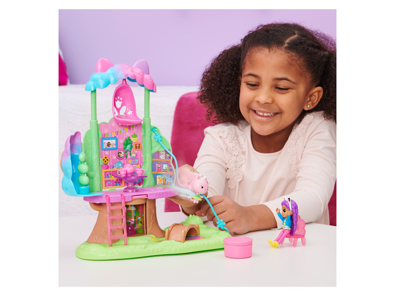 Een meisje speelt met een speelset met een boomhut en poppetjes