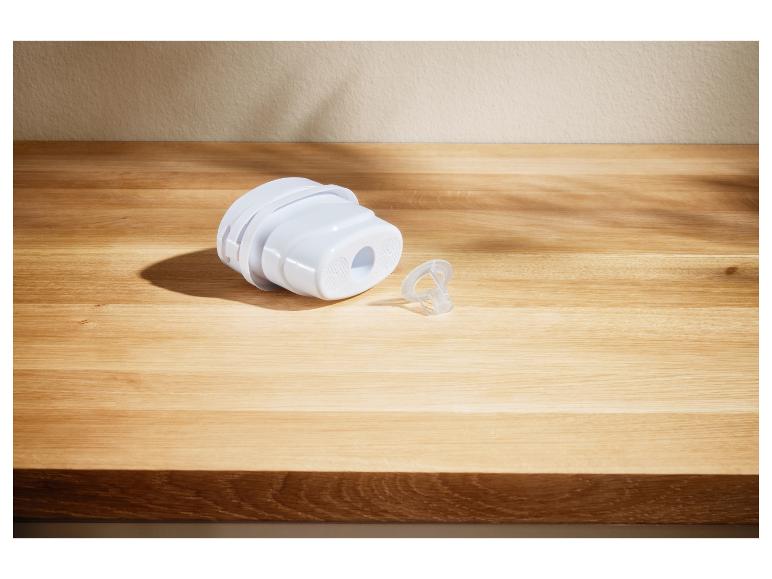 Wit waterfilter en een klein transparant plastic onderdeel op een houten tafel.