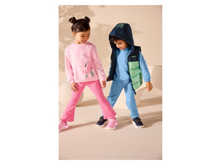 Twee kinderen in roze en blauwe sportsets met sneakers