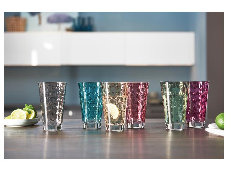 Kleurrijke gehamerde drinkglazen met drankjes en limoenschijfjes op een houten tafel.