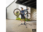 Man repareert een fiets op een fietsreparatiestandaard buiten.