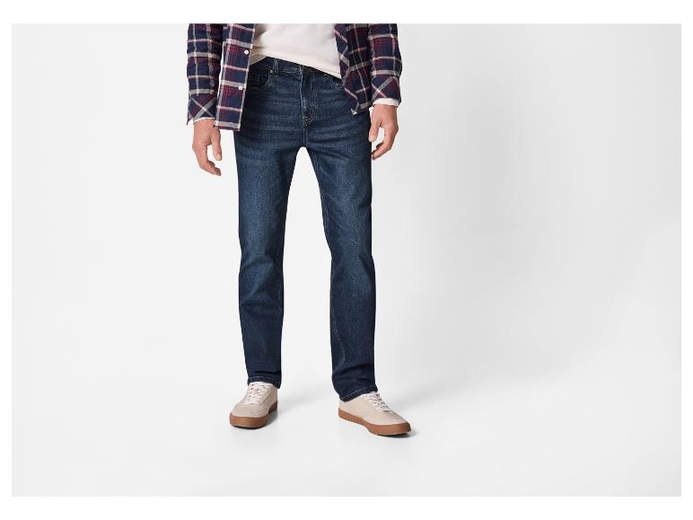 Een persoon draagt een geruit overhemd, donkere jeans en lichte sneakers.