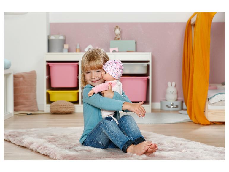 Lachend meisje met een Baby Annabell pop in een kinderkamer met roze vloerkleed.