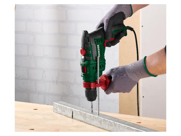 Man met handschoenen gebruikt een PARKSIDE klopboormachine om in een metalen balk te boren.