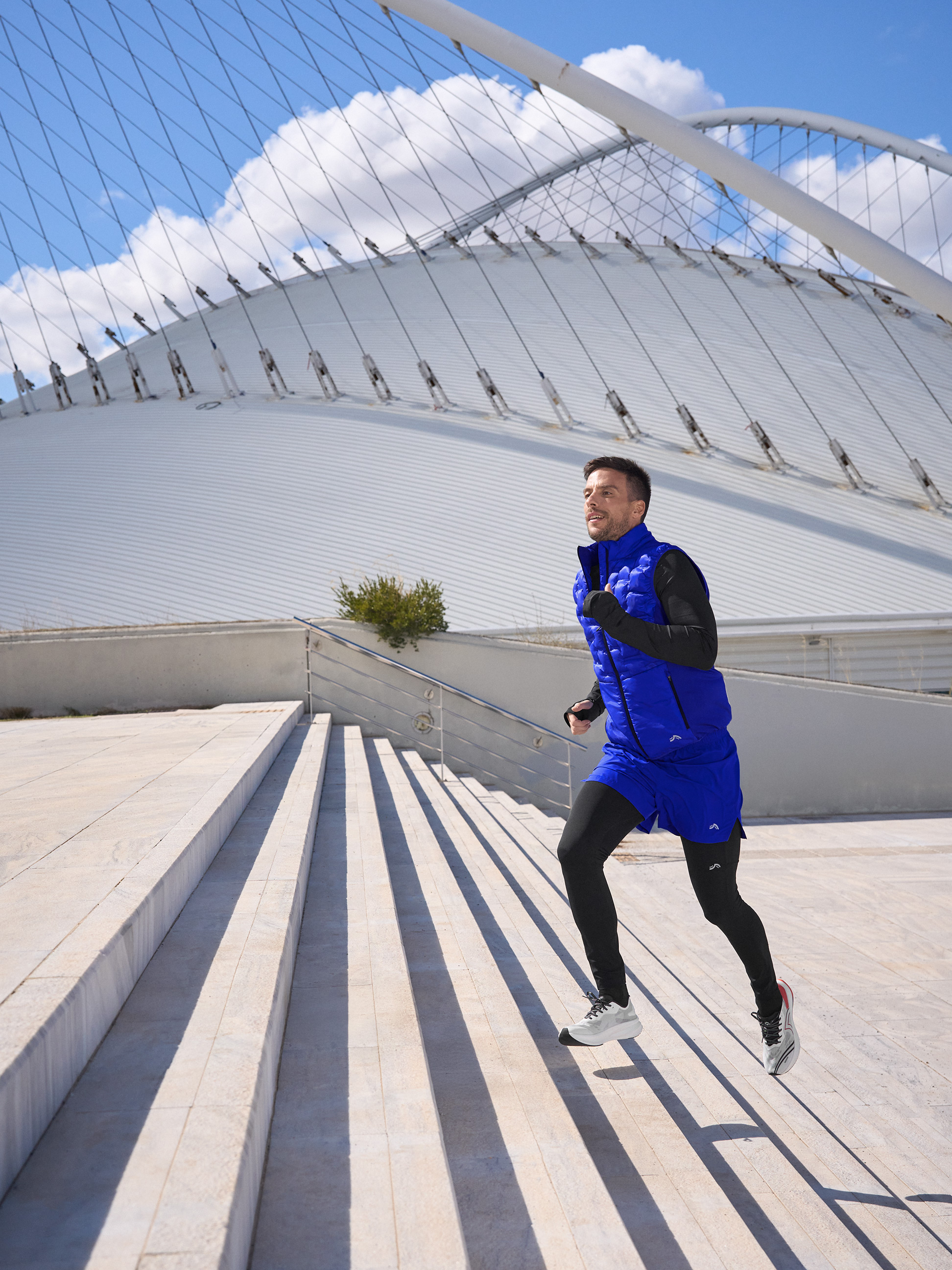 Man in blauw hardloopvest en zwarte legging rent trap op.