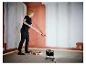 Vrouw schildert muur, verlicht door LIVARNO® werklamp 'The Painter+'.