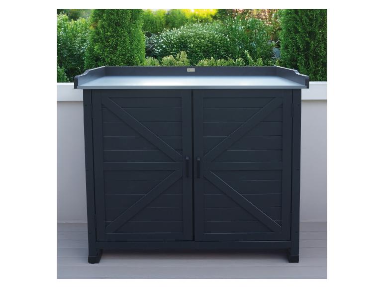 Donkergrijze buitenkast met twee deuren en een licht werkblad, omringd door groene planten.