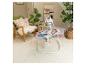 Babywieg met baby in een woonkamer met planten en een stoel.