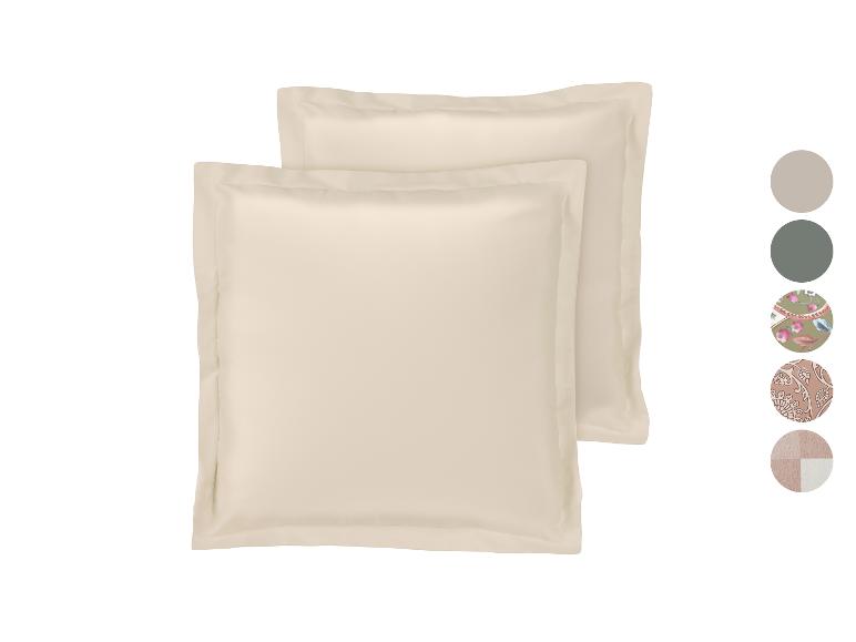 Twee crèmekleurige kussenslopen met een rand, met kleur- en patroonstalen aan de zijkant.